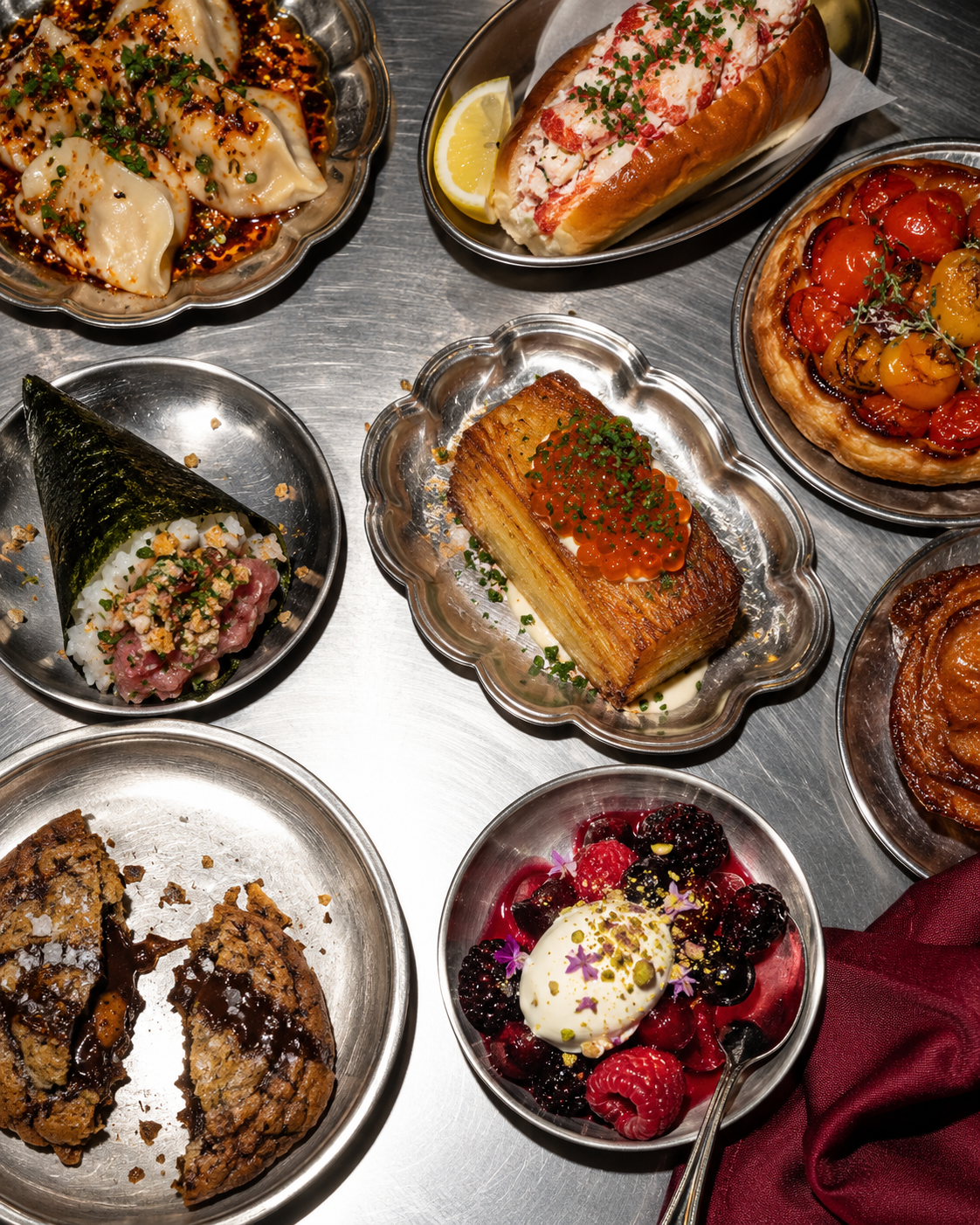 An assortment of sweet and savoury creations on silver dishes across a chef’s kitchen pass